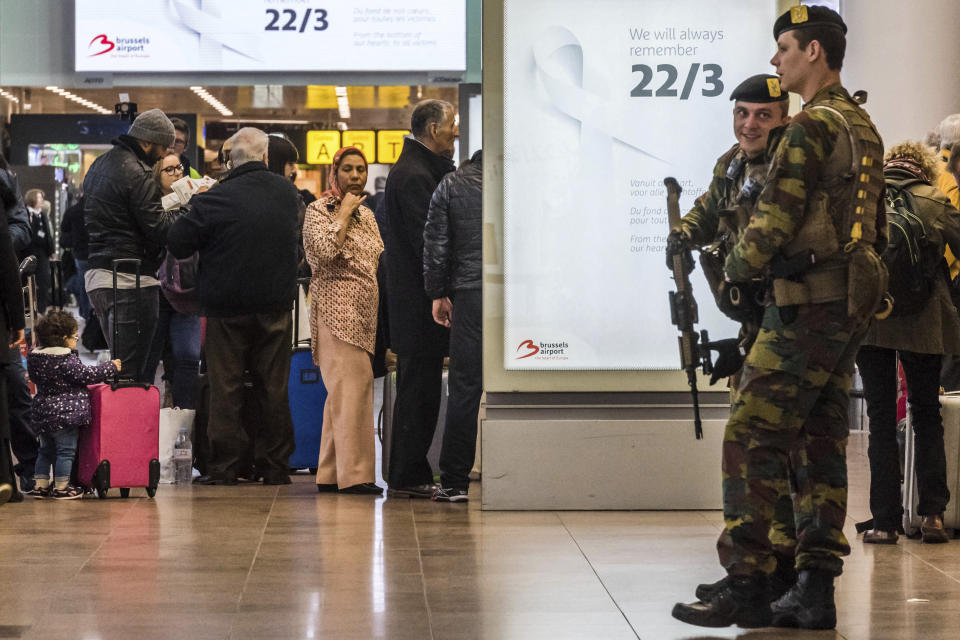 Soldiers patrol as passengers walk through the departure terminal during the one-year anniversary service at Zaventem Airport in Brussels on Wednesday, March 22, 2017. The suicide bombings at the Brussels airport and subway on March 22, 2016, killed 32 people and wounded more than 300 others. (AP Photo/Geert Vanden Wijngaert)