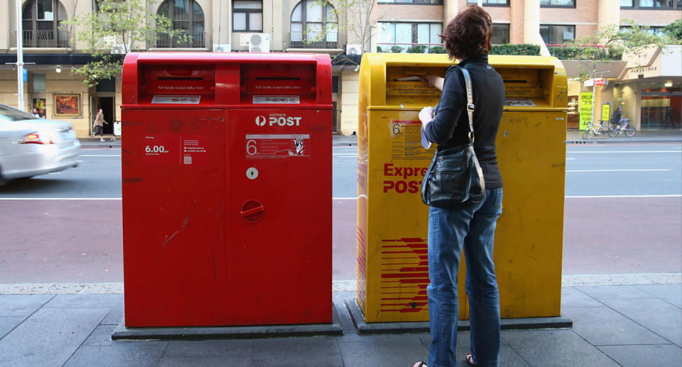 A woman mailing post into an Express Post Letter box