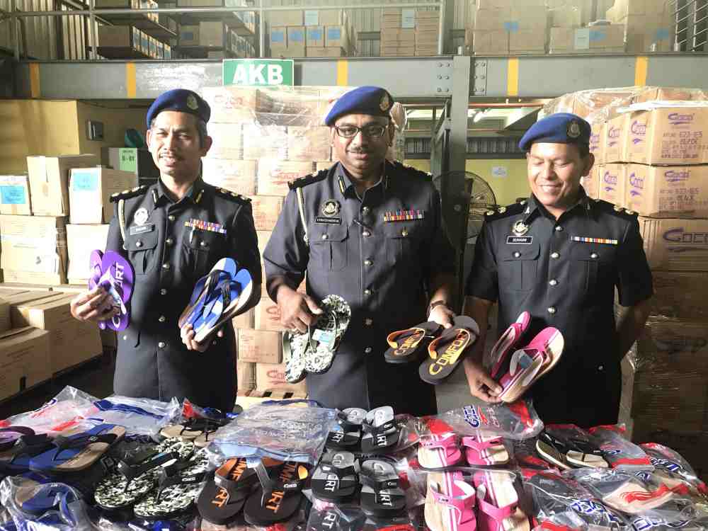 KPDNHEP chief enforcement officer V. Ravichandran (centre) showing the counterfeit sandals, worth more than half a million, seized at a company in Pusing. ― Picture by John Bunyan