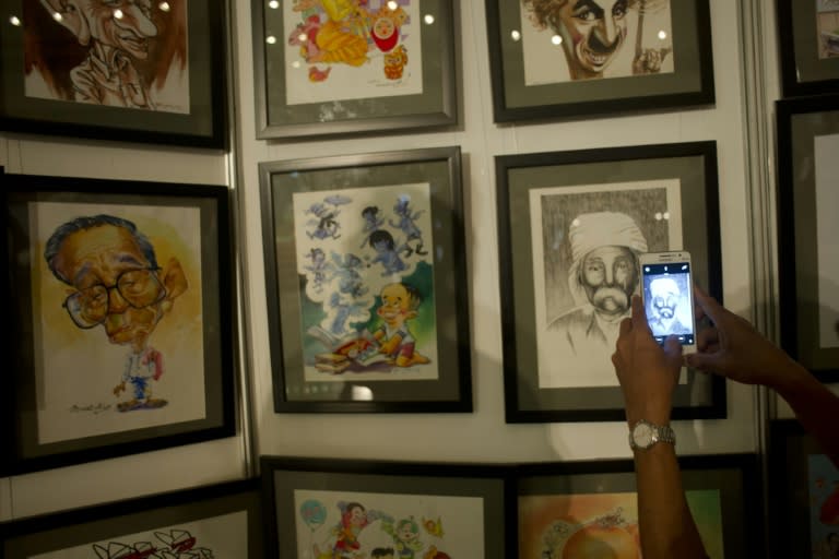 A visitor takes photos at an exhibition of political cartoons in Yangon