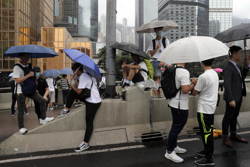 In this photo taken on Wednesday, June 12, 2019, protestors use umbrellas for cover as they gather near the Legislative Council in Hong Kong. Young Hong Kong residents protesting a proposed extradition law that would allow suspects to be sent to China for trial are seeking to safeguard their identities from potential retaliation by authorities employing mass data collection and sophisticated facial recognition technology. (AP Photo/Kin Cheung)