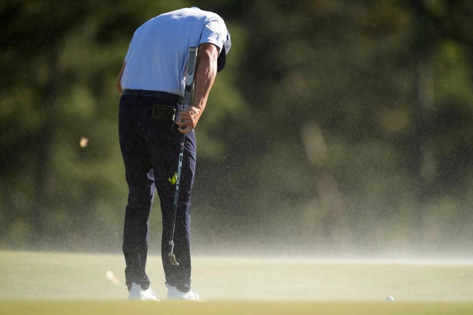 Co-leader Bryson DeChambeau tries to duck out the wind yesterday, with the sand from the bunker thrown up onto the green