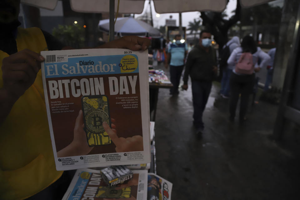 A newspaper vendor shows the front page of a state-run newspaper carrying the headline "Bitcoin Day" in San Salvador, El Salvador, Tuesday, Sept. 7, 2021. Starting Tuesday, all businesses will have to accept payments in Bitcoin, except those lacking the technology to do so, according to a law approved by the congress. (AP Photo/Salvador Melendez)