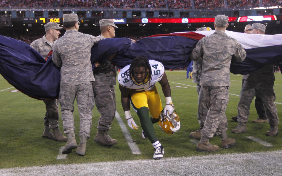 Green Bay Packers Dezman Moses runs under a U.S. flag held by military personnel before their NFL NFC Divisional playoff football game against the San Francisco 49ers in San Francisco, California January 12, 2013. REUTERS/Robert Galbraith (UNITED STATES  - Tags: SPORT FOOTBALL)  