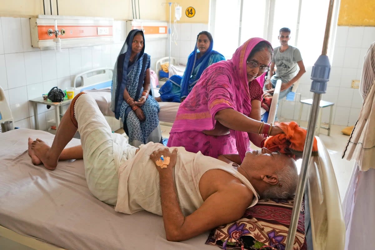 A woman wipes the head of her ailing husband using a wet cloth at the district hospital in Ballia, Uttar Pradesh state (AP)