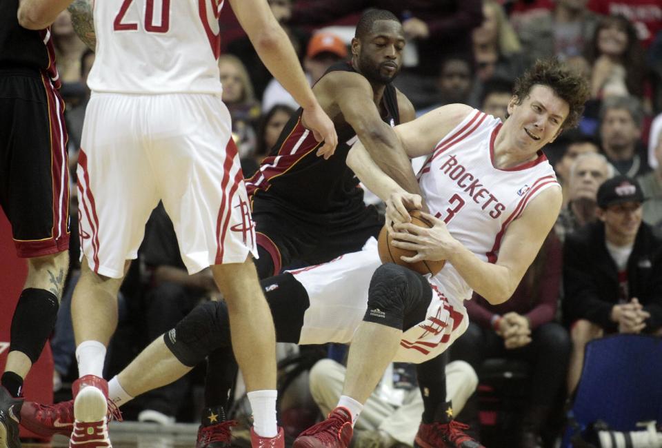 Houston Rockets center Omer Asik (3) struggles with Miami Heat guard Dwyane Wade for a jump ball during the first half of an NBA basketball game, Tuesday, March, 4, 2014, in Houston. (AP Photo/Patric Schneider)