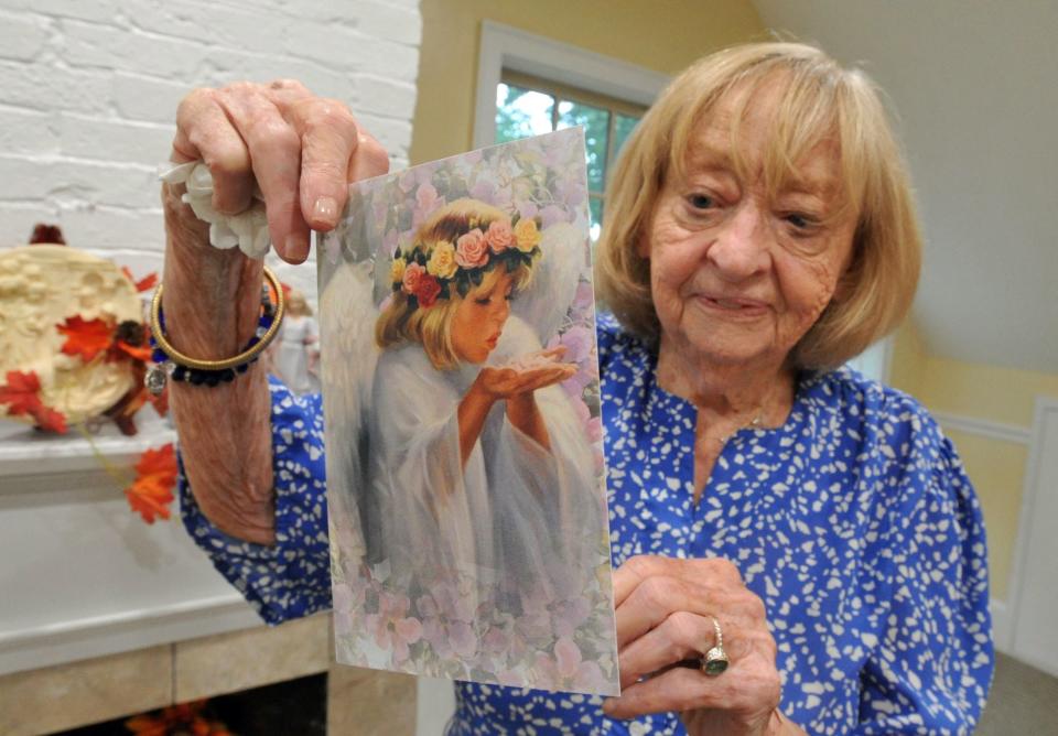 Kate O'Sullivan, 86, of Hingham, who has been working at Celtic Angels Home Health Care in Weymouth for seven years, shows one of the cards she sends out to clients expressing sympathy and support.