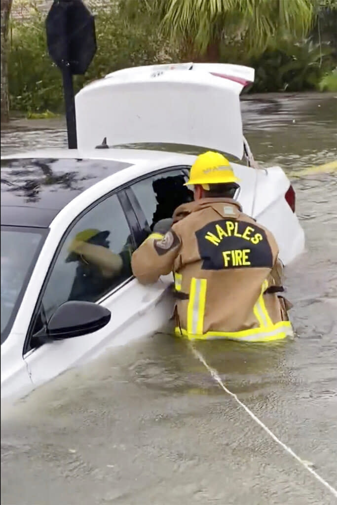 This photo provided by the Naples Fire-Rescue Department shows someone helping rescue a stranded motorist from flooding caused by Hurricane Ian on Sept. 28, 2022, in Naples, Florida.