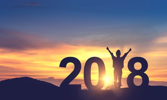 A person celebrating on a hill with the numbers 2018.