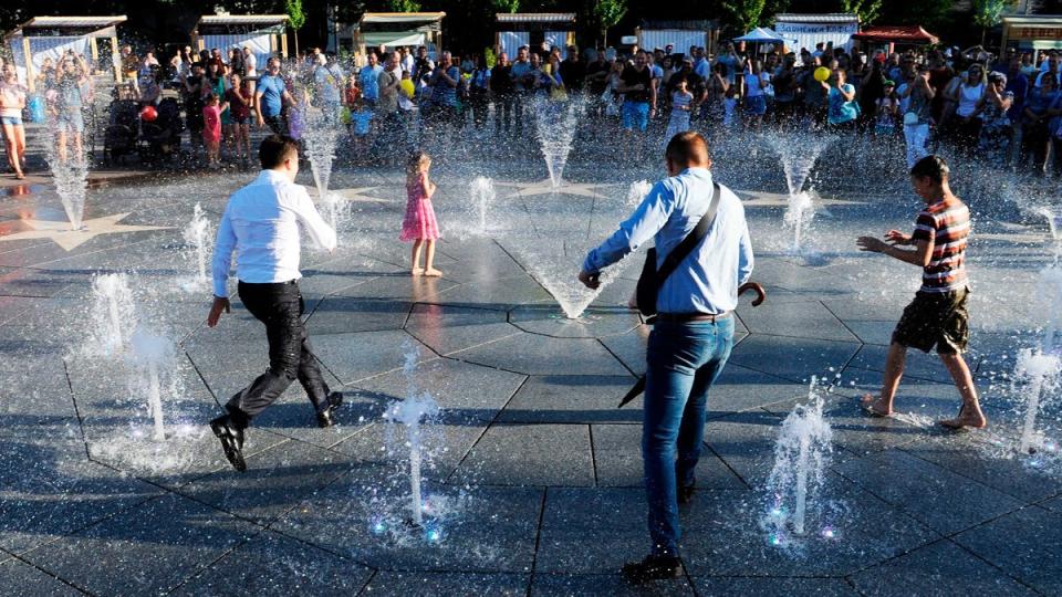 El presidente Volodymyr Zelensky (izq) y varios niños juegan en una fuente durante su primera visita oficial a Mariupol en 2019.