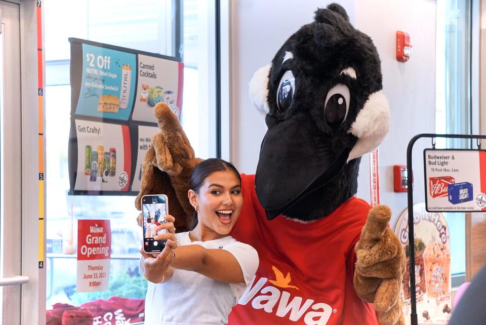 Samantha Gutierrez takes a selfie with Wally Goose, the mascot for Wawa, at the grand opening for a new store in Lantana on June 15, 2023.