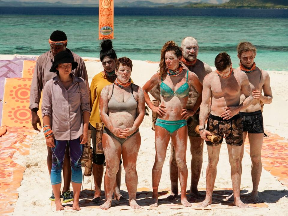 "Survivor: Island of the Idols" players standing on the beach covered in sand during a challenge.