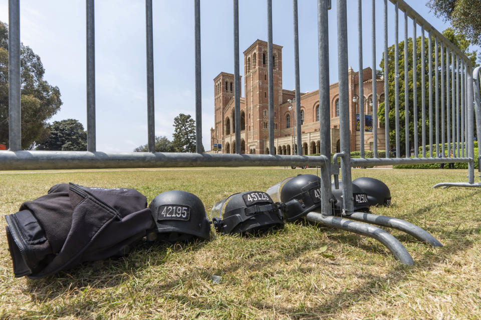 Police riot gear lays on the grass next to steel barriers set up outside Royce Hall at the UCLA campus in Los Angeles on Friday, May 3, 2024. More than 200 people were taken into custody at the university early Thursday, after hundreds of protesters defied orders to leave, some forming human chains as police fired flash-bangs to break up the crowds. (AP Photo/Damian Dovarganes)