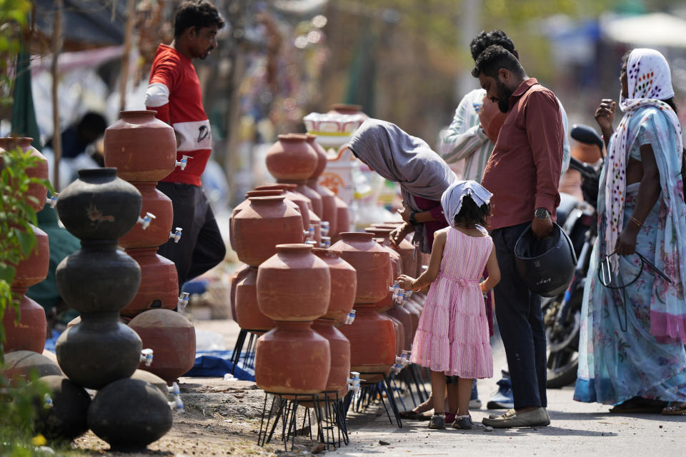 People shop for earthen water vessels, known locally as poor man's refrigerator, from a roadside vendor in Hyderabad, India, Thursday, May 2, 2024. (AP Photo/Mahesh Kumar A.)