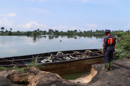 A member of the Nigerian security forces stands next to a barge holding diesel produced from a nearby illegal refinery near the village of Bodo in the Niger Delta, Nigeria August 2, 2018. Picture taken August 2, 2018. REUTERS/Ron Bousso