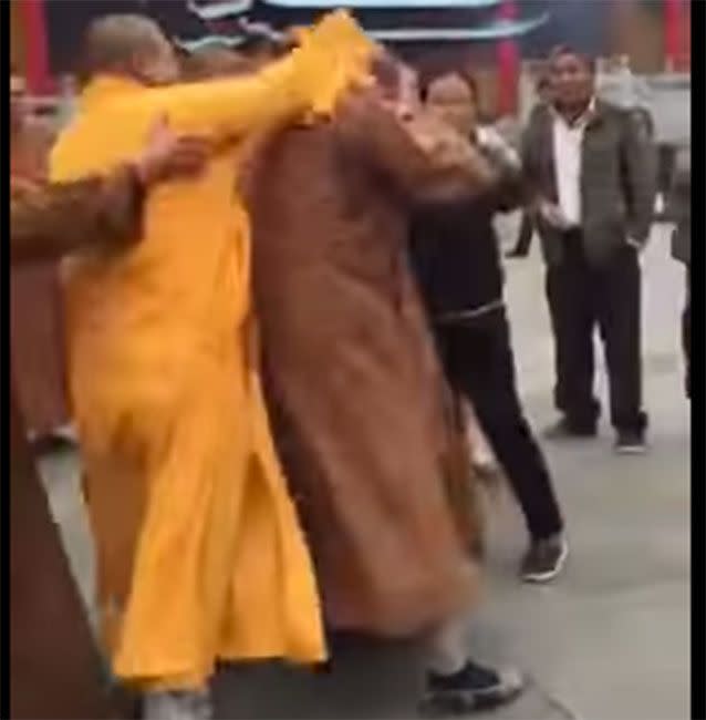 A third monk launches at two others, bashing one of them on the head with a mobile phone. Photo: Sina.com.