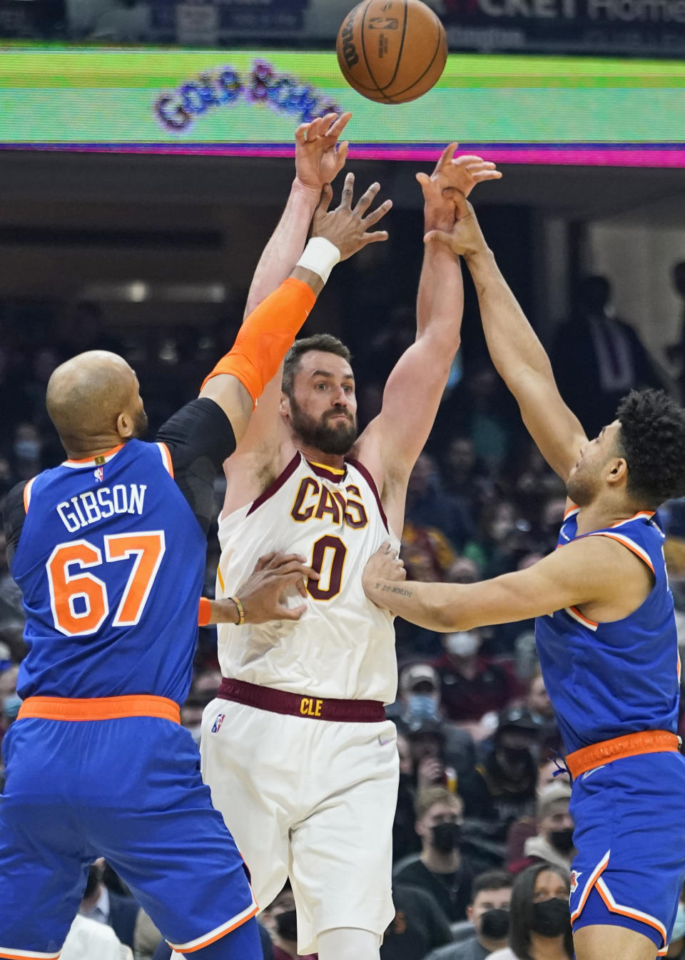 Cleveland Cavaliers' Kevin Love (0) passes over New York Knicks' Taj Gibson (67) and Quentin Grimes (6) in the first half of an NBA basketball game, Monday, Jan. 24, 2022, in Cleveland. (AP Photo/Tony Dejak)