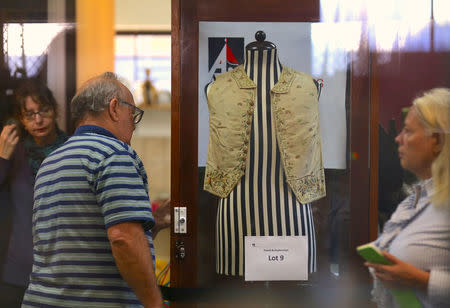 Potential buyers can be seen near the display case containing a 250-year-old embroidered silk waistcoat that belonged to Captain James Cook on a mannequin at Aalders Auctions house in Sydney, Australia, March 26, 2017. REUTERS/Steven Saphore