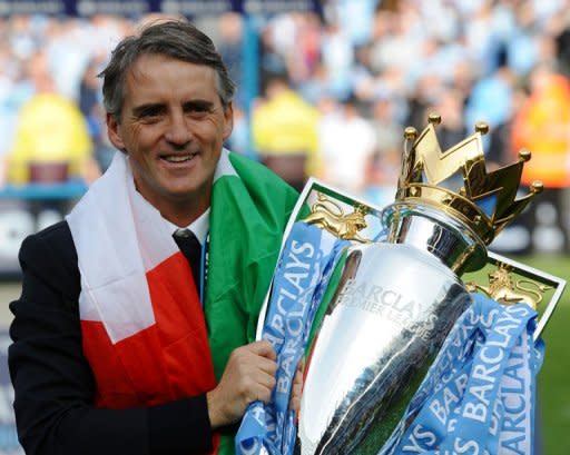 Manchester City's manager Roberto Mancini celebrates on the pitch with the Premier League trophy after their thrilling 3-2 victory over Queens Park Rangers, at The Etihad stadium in Manchester, on May 13. With their win, Man City secured their first league title since 1968