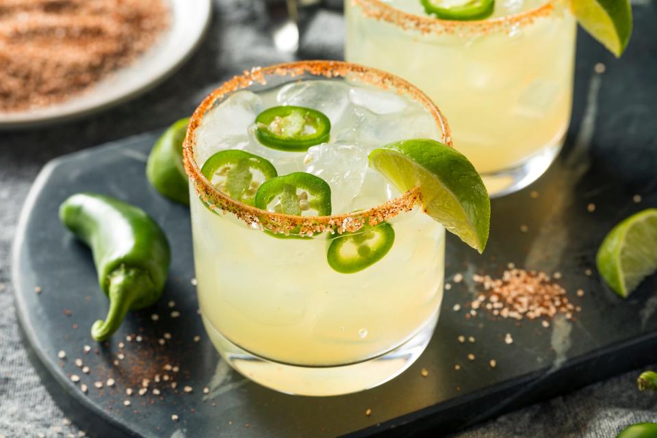 A spicy margarita with a chili salt rim garnished with jalapeno slices and a lime wedge