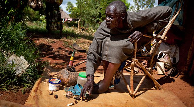 Kenyan witch doctor John Dimo, not linked to the alleged Ugandan sacrifices, throwing shells, bones, and other magic items to predict the US election outcome. Source: AAP