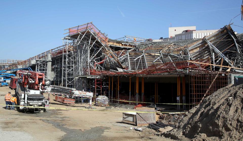 Men work near the site where section of a parking structure under construction collapsed Friday March 28, 2014 in Los Angeles. No one was trapped or hurt, authorities said. (AP Photo/Nick Ut)