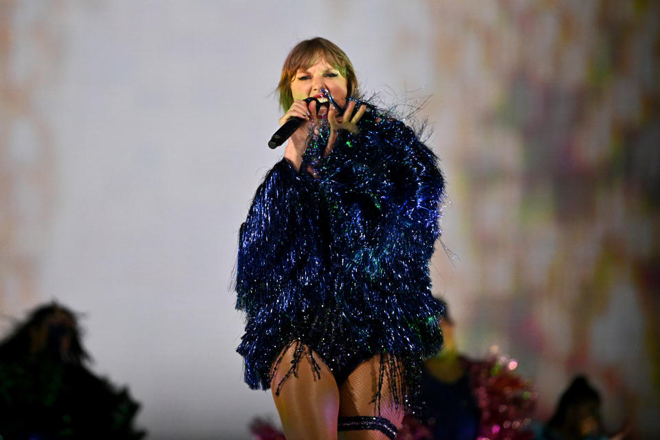 Taylor Swift in a shimmering navy blue jacket during The Eras Tour