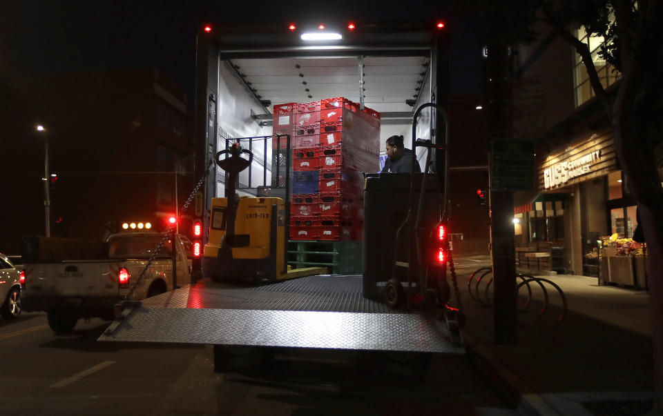 FILE - In this March 27, 2020, file photo, a worker unloads food products from a truck outside Gus's Community Market early in the morning, in San Francisco. From South Africa to Italy to the U.S., grocery workers — many in low-wage jobs — are manning the front lines amid worldwide lockdowns, their work deemed essential to keep food and critical goods flowing. (AP Photo/Ben Margot, File)