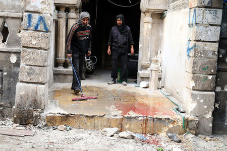 Men wash the blood stained ground after strikes on rebel-held besieged al-Zebdieh district, in Aleppo Syria December 5, 2016. REUTERS/Abdalrhman Ismail