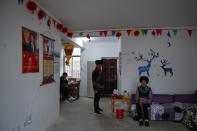 An ethnic minority Yi family rests near posters of Chinese President Xi Jinping in their village house built by the Chinese government in Ganluo county, southwest China's Sichuan province on Sept. 10, 2020. Communist Party Xi’s smiling visage looks down from the walls of virtually every home inhabited by members of the Yi minority group in a remote corner of China’s Sichuan province. Xi has replaced former leader Mao Zedong for pride of place in new brick and concrete homes built to replace crumbling traditional structures in Sichuan’s Liangshan Yi Autonomous Prefecture, which his home to about 2 million members of the group. (AP Photo/Andy Wong)