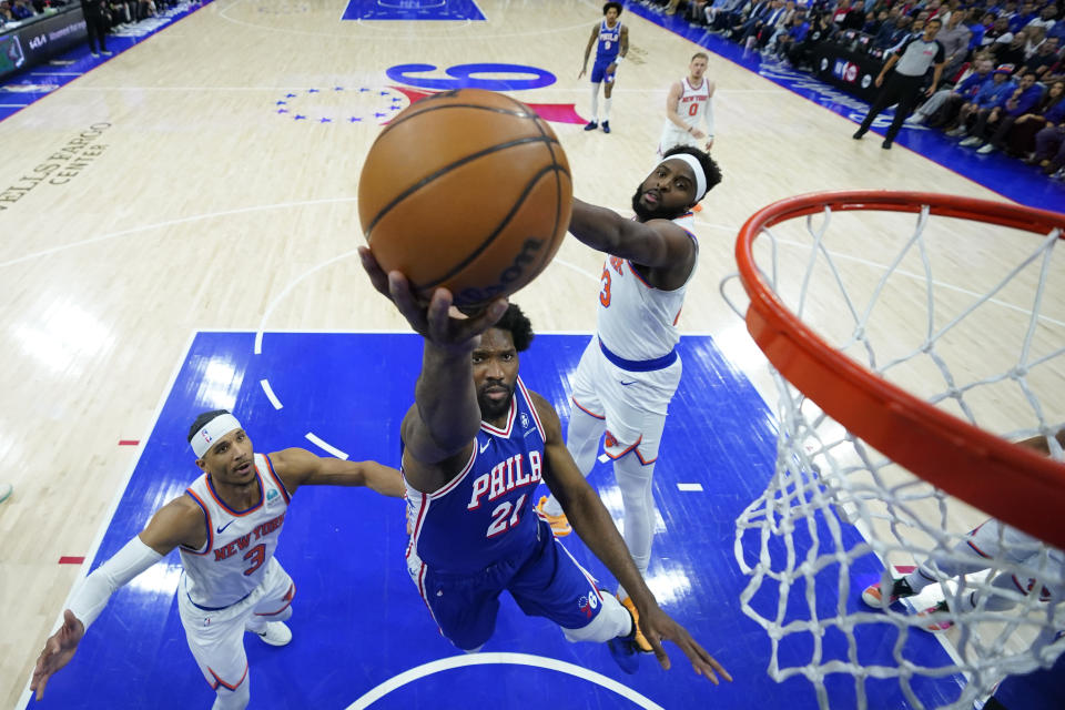 Philadelphia 76ers' Joel Embiid, center, goes up for a shot against New York Knicks' Mitchell Robinson, right, and Josh Hart during the first half of Game 3 in an NBA basketball first-round playoff series, Thursday, April 25, 2024, in Philadelphia. (AP Photo/Matt Slocum)