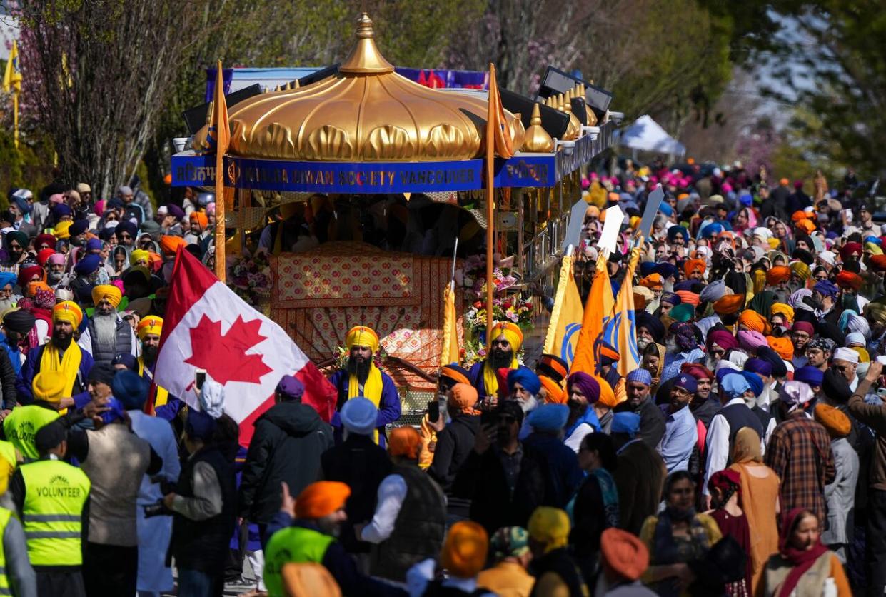 People march with the main float during the Vaisakhi parade in Vancouver, on Saturday, April 13, 2024. Vaisakhi is a significant holiday on the Sikh calendar, commemorating the establishment of the Khalsa in 1699 and marking the beginning of the Punjabi harvest year. (Darryl Dyck/The Canadian Press - image credit)