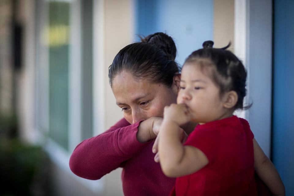 Erika Lopez weeps while holding her 1-year-old daughter, Estrellita