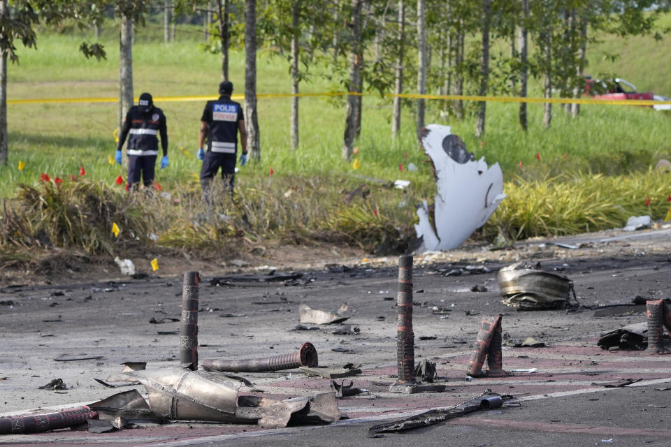 Members of the fire and rescue department inspect the crash site of a small plane in Shah Alam district, Malaysia, Thursday, Aug. 17, 2023. Police say a small aircraft has crashed in the suburb in Malaysia's central Selangor state, with multiple bodies recovered. (AP Photo/Vincent Thian)