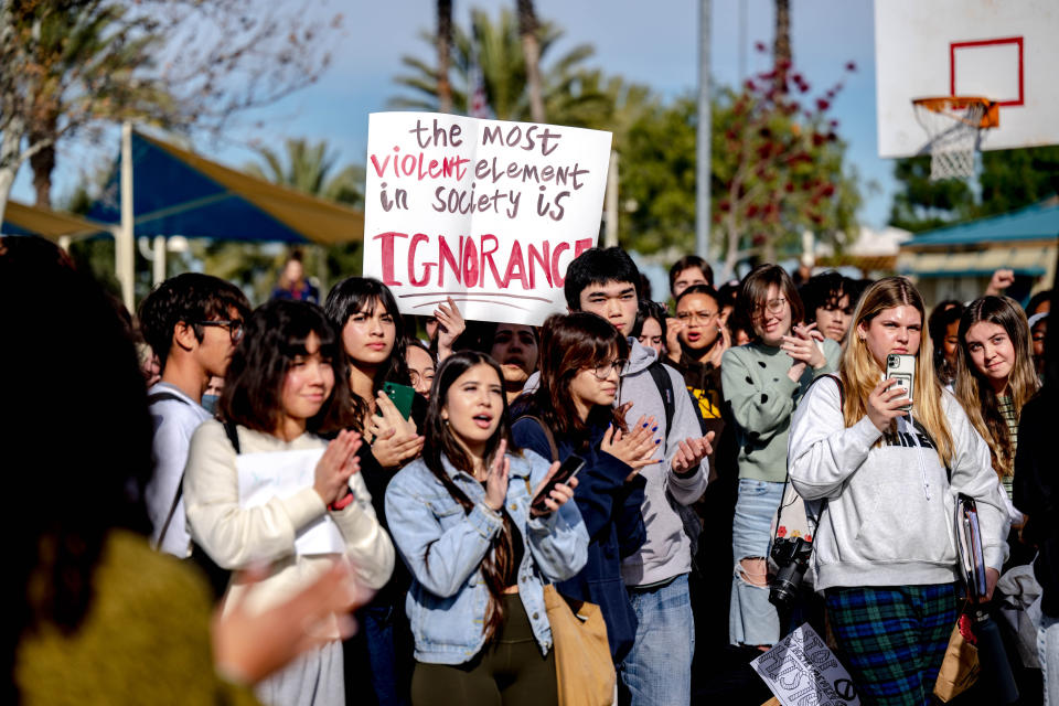 Temecula high school students leave campus in protest. One holds a sign reading: The most violent element in society is ignorance.