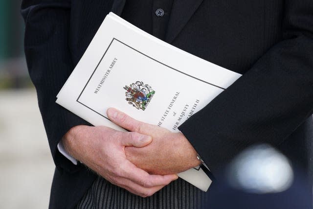 A mourner carrying an order of service