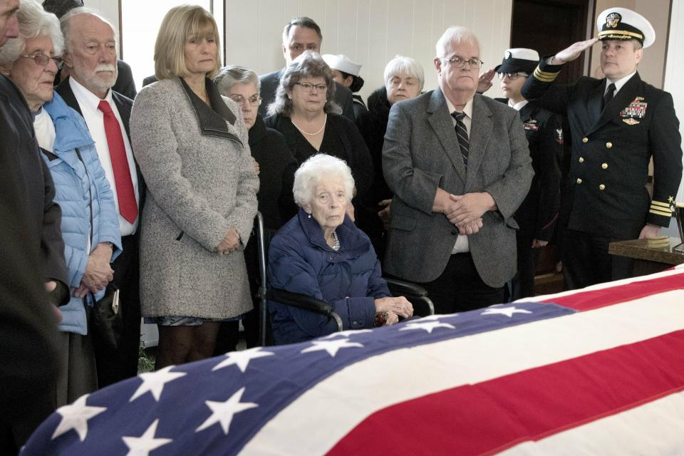 Rita Mendonsa, center, sits in front of her husband George's flag-draped casket during funeral services at St. Columba Cemetery in Middletown, R.I., Friday, Feb. 22, 2019. George Mendonsa, the sailor sailor photographed kissing a woman in Times Square at the end of World War, died Sunday at age 95. (AP Photo/Michael Dwyer)