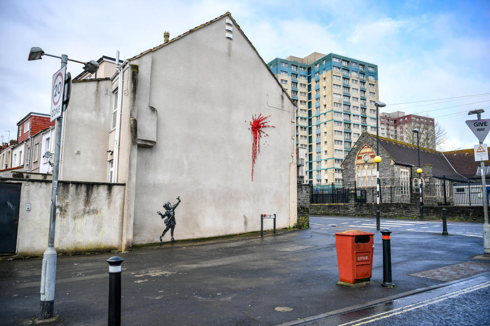 L'ultima creazione dello street artist britannico sulla facciata di un edificio a Bristol, sua città natale in Inghilterra: una bambina con una fionda di fronte a un’esplosione rossa, fatta di petali e fiori di plastica, forse il cuore infranto di Cupido. (Photo by Ben Birchall/PA Images via Getty Images)