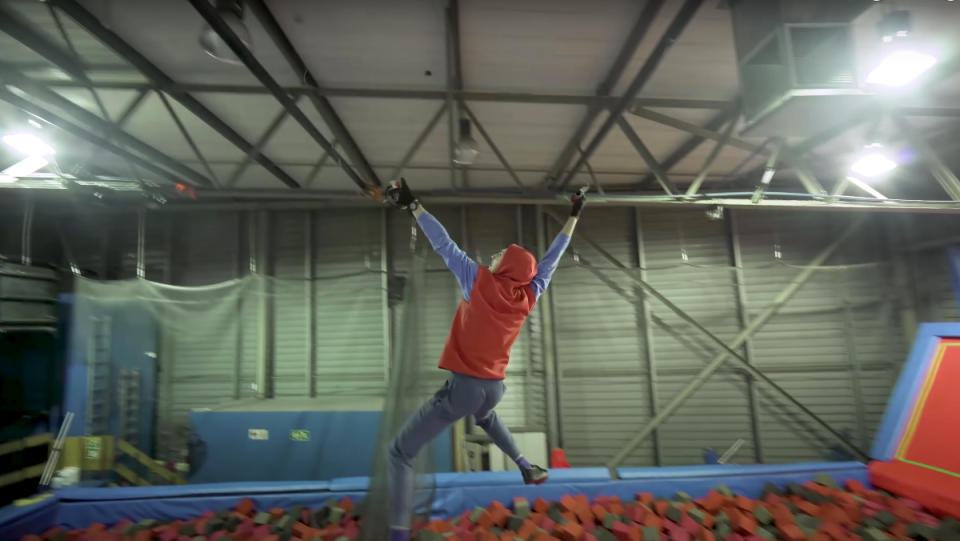 An engineer using his IRL Spider-Man web shooters to swing over a pit of foam cubes.