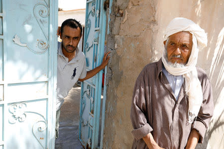 Hamid, 28, an unemployed member of a family of six disabled people, is seen with his father in front of their house in Remada, October 12, 2018. Picture taken October 12, 2018. REUTERS/Zoubeir Souissi