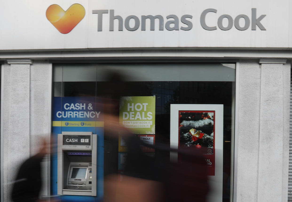 People walk past a closed Thomas Cook travel shop in London, Monday, Sept. 23, 2019. British tour company Thomas Cook collapsed early Monday after failing to secure emergency funding, leaving tens of thousands of vacationers stranded abroad. (AP Photo/Frank Augstein)