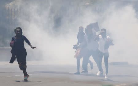 Civilians make their way through tear gas that was fired by riot policemen to disperse a protest by supporters of Kenyan opposition National Super Alliance (NASA) coalition, along a street in Nairobi, Kenya October 16, 2017. REUTERS/Thomas Mukoya