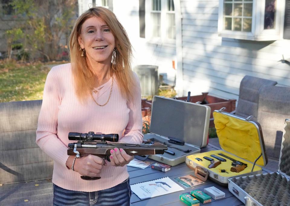 Gun owner Christine Joyce Brown holds a Remington XP-100 Silhouette pistol next to an assortment of other guns she uses at shooting ranges while at her home in Milwaukee on Nov. 15.
