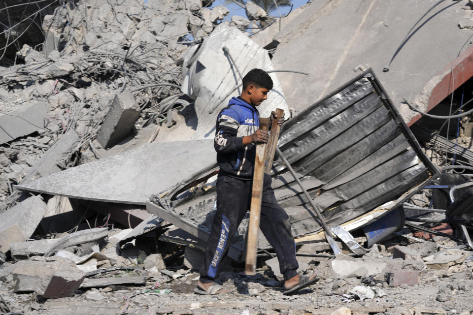 Palestinians salvage belongings from the rubble of a building of the Hamad family destroyed in an Israeli strike in Deir al Balah, Gaza Strip, Friday, Dec. 29, 2023. (AP Photo/Adel Hana)