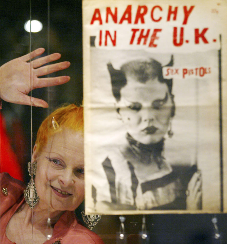 FILE - Designer Vivienne Westwood looks through the glass toward the media during a photocall at a retrospective exhibition to celebrate her 30 years in the fashion industry, at the Victoria and Albert Museum in London, Tuesday March 30, 2004. Westwood, an influential fashion maverick who played a key role in the punk movement, died Thursday, Dec. 29, 2022, at 81. (AP Photo/Alastair Grant, File)