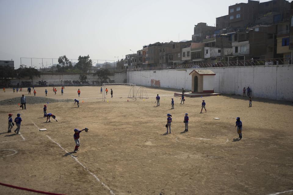 Venezuelan children play baseball, front, while Peruvian children play soccer in a public field in the San Juan de Lurigancho area, on the outskirts of Lima, Peru, Saturday, May 11, 2024. Immigrants, mainly Venezuelans, have opened five baseball academies in Peru's capital. (AP Photo/Martin Mejia)