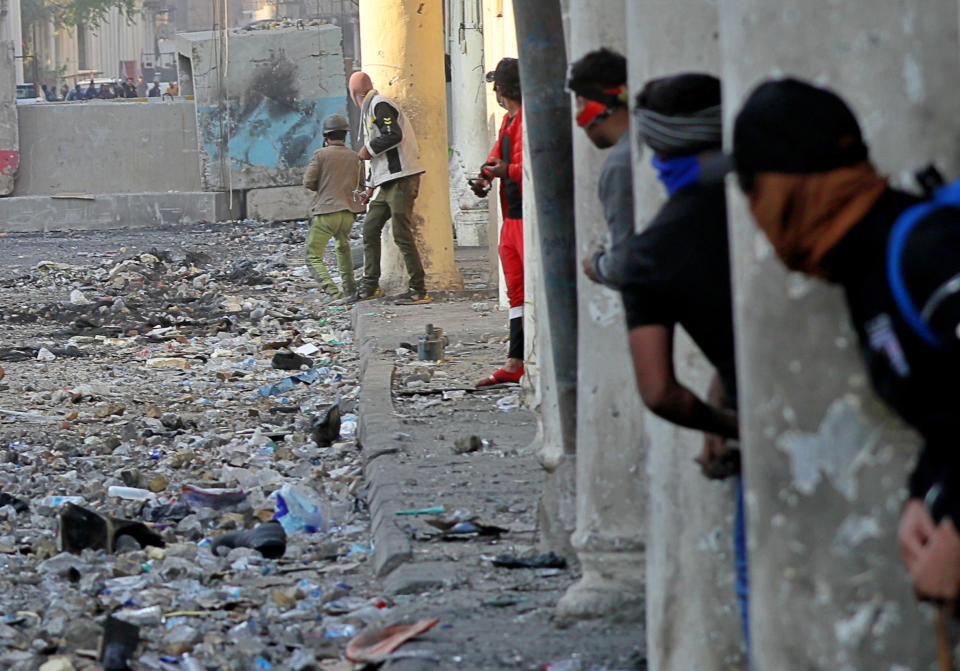 FILE - In this Nov. 24, 2019 file photo, demonstrators take cover during clashes between security forces and anti-government protesters in, Baghdad, Iraq. While the 2011 Arab Spring uprisings that took place in Egypt, Tunisia, Libya and Syria were directed at long-ruling autocrats, the current economically driven uprisings are directed at corrupt political elites who have failed at providing their people with basic services. (AP Photo/Khalid Mohammed, File)