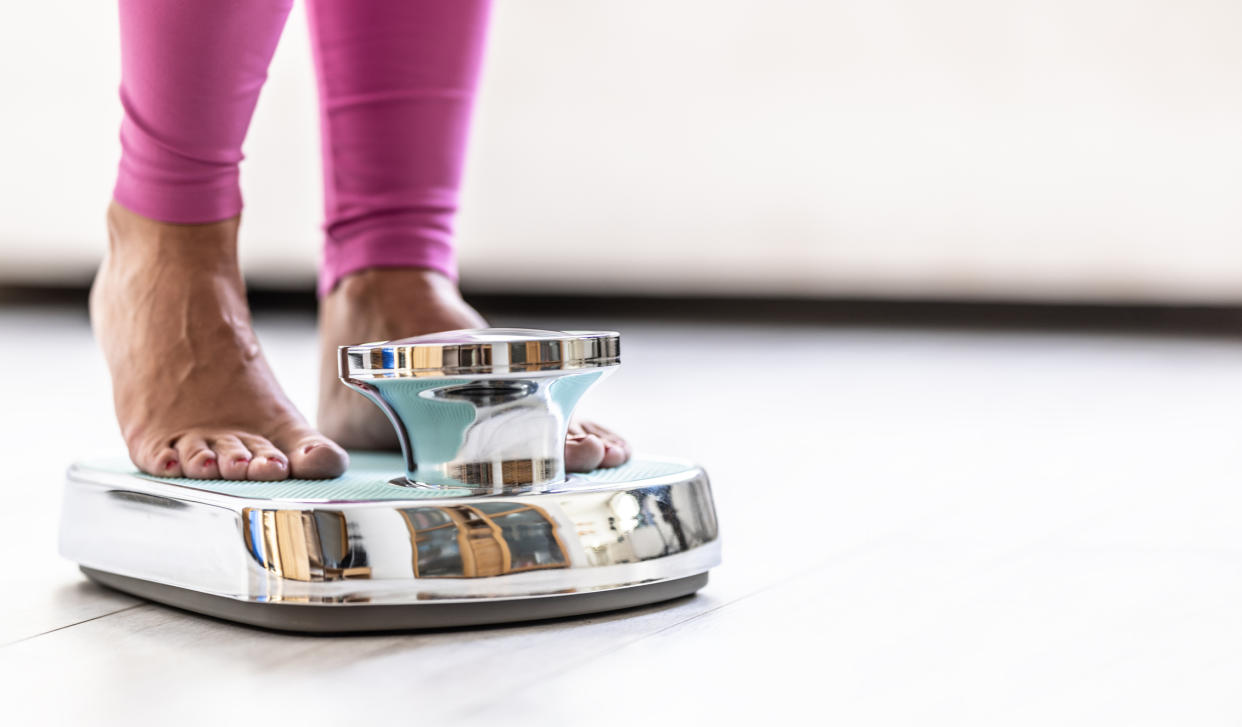 Woman standing on scale; close-up of legs.