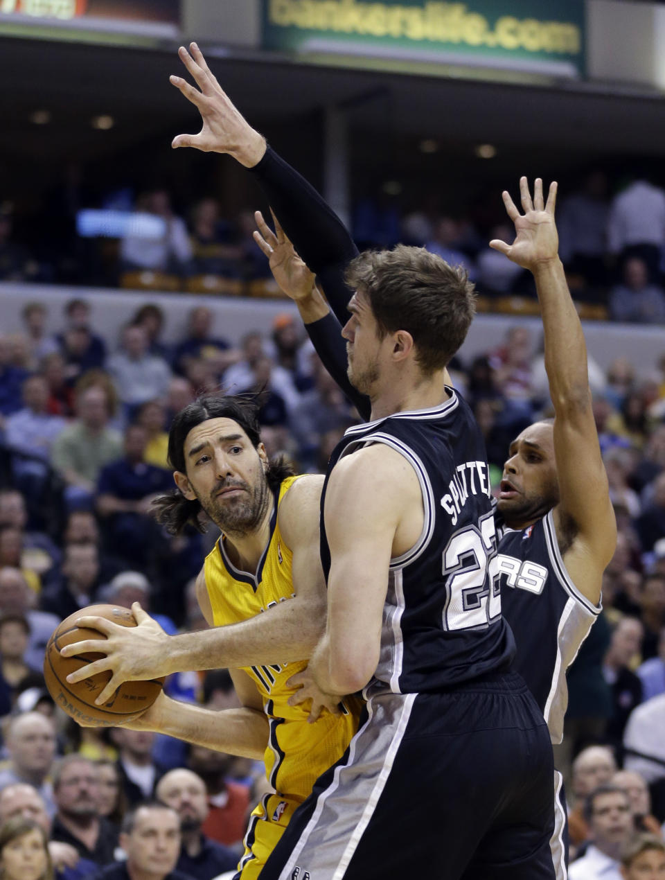 Indiana Pacers forward Luis Scola, left, is trapped by San Antonio Spurs center Tiago Splitter, center, and guard Patty Mills in the first half of an NBA basketball game in Indianapolis, Monday, March 31, 2014. (AP Photo/Michael Conroy)