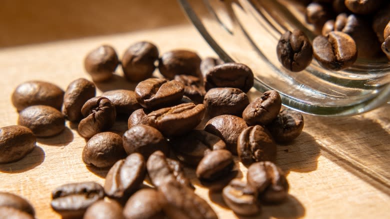 Close-up of roasted coffee beans spilling from a jar